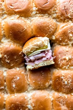 a ham and cheese slider sitting on top of bread rolls