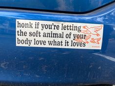 a sticker on the back of a blue car that says honk if you're letting the soft animal of your body love what it loves