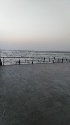 a bench sitting on top of a sidewalk near the ocean