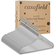 a set of 50 velvet suit hangers in front of a cardboard box and packaging