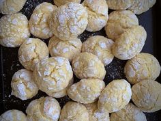 a pile of powdered sugar cookies sitting on top of a black tray