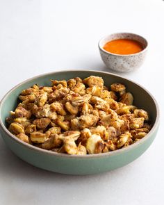 a bowl filled with nuts next to a cup of sauce