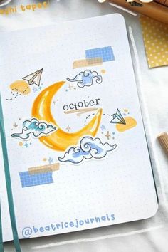 an open notebook with the word october written on it next to some crayons