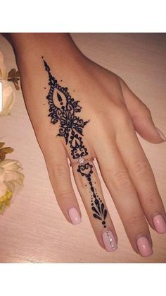 a woman's hand with a black and white henna tattoo design on it