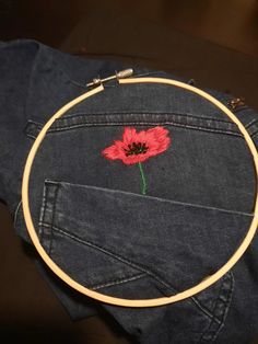 a red flower is embroidered on the back of a pair of blue jean pants with gold hoop