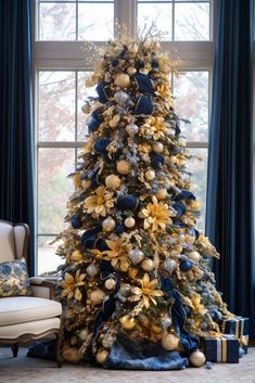 a decorated christmas tree in front of a window with blue and gold decorations on it