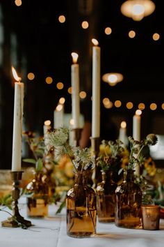 there are many vases with flowers and candles on the table