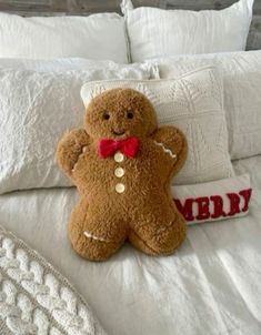 a brown teddy bear sitting on top of a white bed next to pillows and blankets