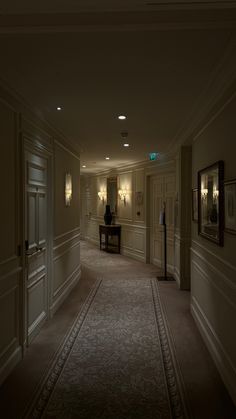 an empty hallway in a hotel with lights on the walls and carpeted flooring