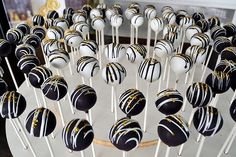 cake pops with white and black stripes are arranged in a circle on a plate, ready to be eaten