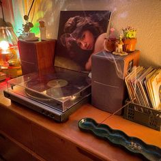 a record player sitting on top of a wooden table next to a lamp and pictures