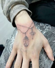 a person's hand with a rosary and cross tattoo on the middle of it