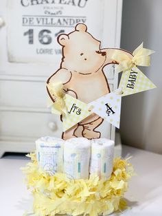 a baby shower centerpiece made out of diapers and yellow ribbon with a teddy bear on top