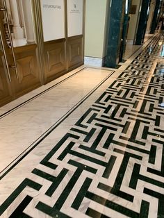 a marble floor with black and white designs on the ground in front of two doors