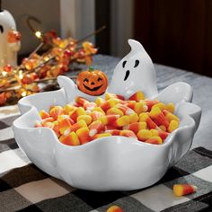 a white bowl filled with candy corn sitting on top of a table