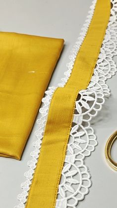 a pair of scissors next to a yellow piece of cloth with white lace on it