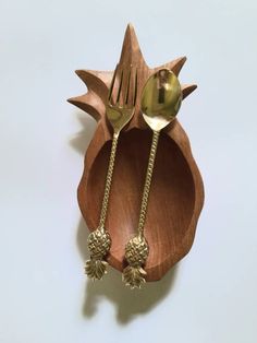 a wooden spoon and fork holder with two pineapples on the forks inside it