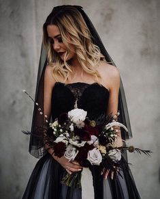 a woman in a black wedding dress holding a bouquet