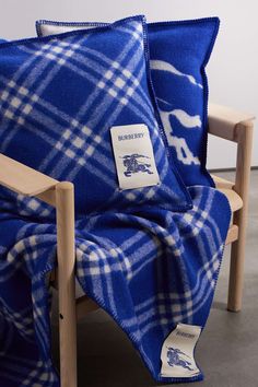 a blue and white plaid blanket sitting on top of a wooden chair next to a pillow