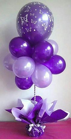 purple and white balloons in a vase on a table