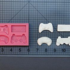 three video game controller molds are shown on a table next to a measuring ruler