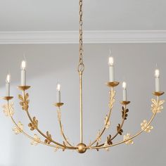 a gold chandelier with candles hanging from it's center and leaves on the bottom