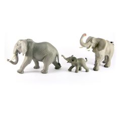 three toy elephants are walking with one baby elephant and the other is an adult elephant