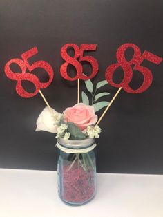 there is a vase with flowers in it and the numbers are made out of red glitter