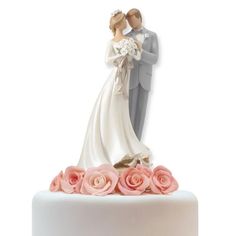 a bride and groom figurine on top of a wedding cake with pink roses