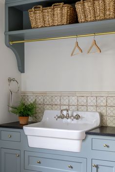 a white sink sitting on top of a kitchen counter next to a shelf filled with baskets