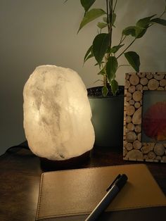 a white rock lamp sitting on top of a desk next to a pen and notebook