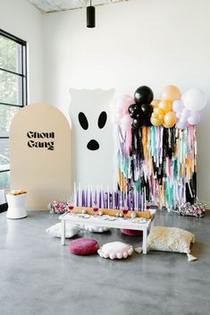 a birthday cake with candles and balloons in the shape of a ghost is on display