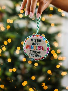 a hand holding a christmas ornament that says it's the most wonderful time of the year