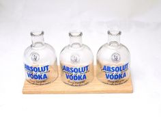 three empty vodka bottles sitting on top of a wooden tray with the label absolut vodka