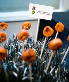 there are many oranges on sticks in the grass with a business card stuck to them