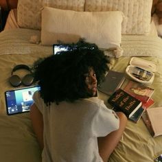 a woman laying in bed with her laptop and books