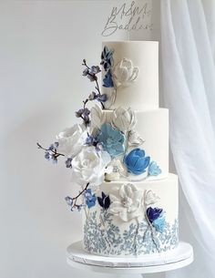 a three tiered cake with blue and white flowers