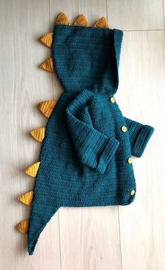 a blue sweater with yellow spikes is laying on the floor next to a stuffed animal