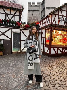 a woman standing in front of a building with christmas decorations on the outside and inside