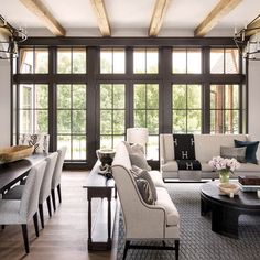 a living room filled with lots of furniture next to a large window covered in wood beams