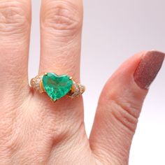 Kapow! 4ct Colombian emerald heart set in 18k yellow gold flanked with .50cts of diamonds. Emerald is an incredible glowing green with natural inclusions and measures 11.6x11.7mm. Ring size 8.75.Sizing availableLayaway available Colombian Emeralds, Turquoise Ring, Statement Rings, Heart Ring, Emerald, Ring Size, Diamonds, Yellow Gold, The Incredibles