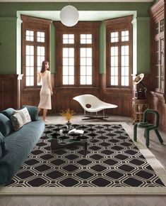 a woman standing in the middle of a living room with green walls and wood paneling