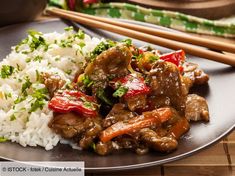 a plate topped with meat and rice next to chopsticks