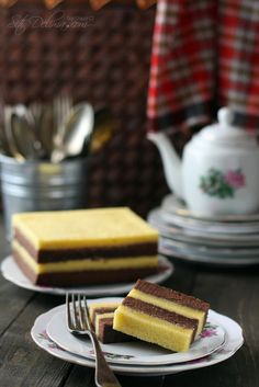 there is a piece of cake on the plate next to a fork and tea pot