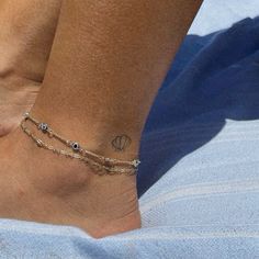 a woman's foot with a tattoo on it and a chain around the ankle