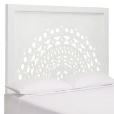 a white bed with an intricate headboard and pillow on it's side,