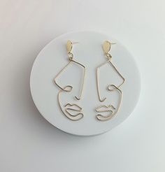 Made to order — no two pairs are exactly the same. Silver earrings and earring posts are made with stainless steel, and the gold pair with tarnish-resistant brass. These materials are hypoallergenic and ultra-lightweight for a creative statement earring. Each pair is placed on a watercolor print that celebrates uniqueness — just like your new favorite earrings. Made to order and shipped in 5-7 business days. Dimensions — Length (including hardware): 2.75 inWidth: 0.875 in Minimalist Handmade Stainless Steel Earrings, Handmade Minimalist Stainless Steel Earrings, Minimalist Metal Plug Earrings As Gift, Brass Wire Earrings, Ears Pierced, Earrings Minimal, Abstract Face, Statement Earring, Abstract Faces