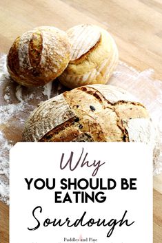 two loaves of bread sitting on top of a wooden table next to a sign that says why you should be eating sourdough