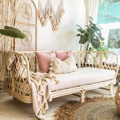 a wicker day bed with pink and white pillows on it in a living room