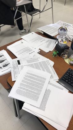 many papers are spread out on a table with a keyboard and mouse in the foreground